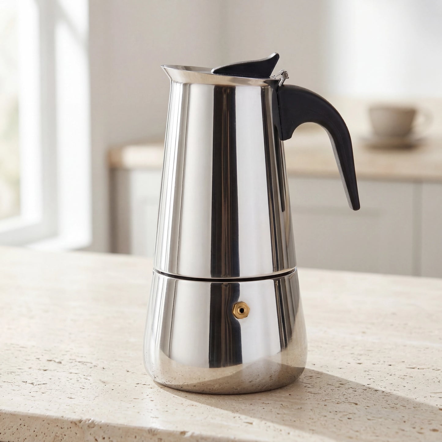 Cafetière italienne percolateur en inox posée sur un plan de travail de cuisine.