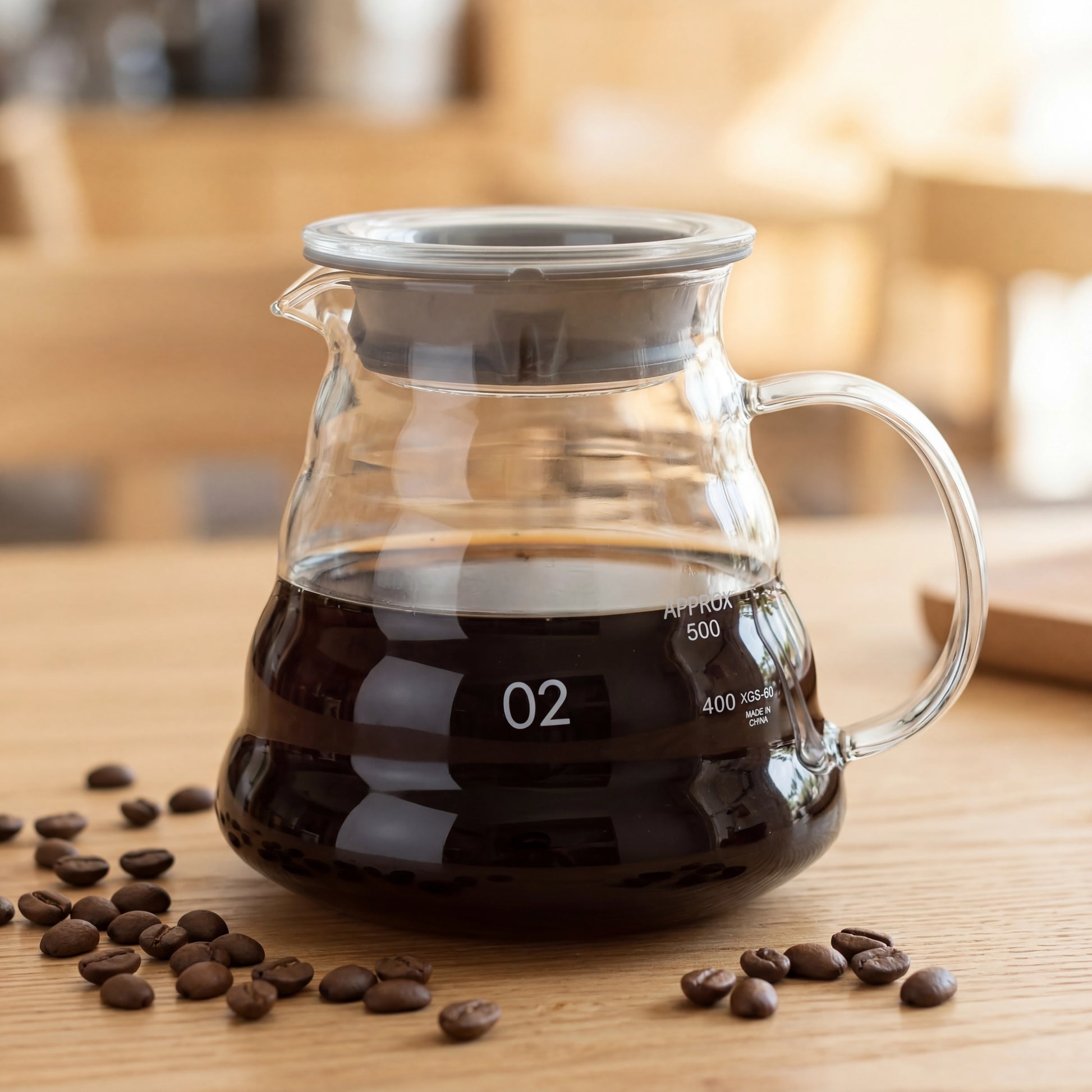 Carafe à café en verre borosilicate remplie de café posée sur une table en bois avec des grains de café.