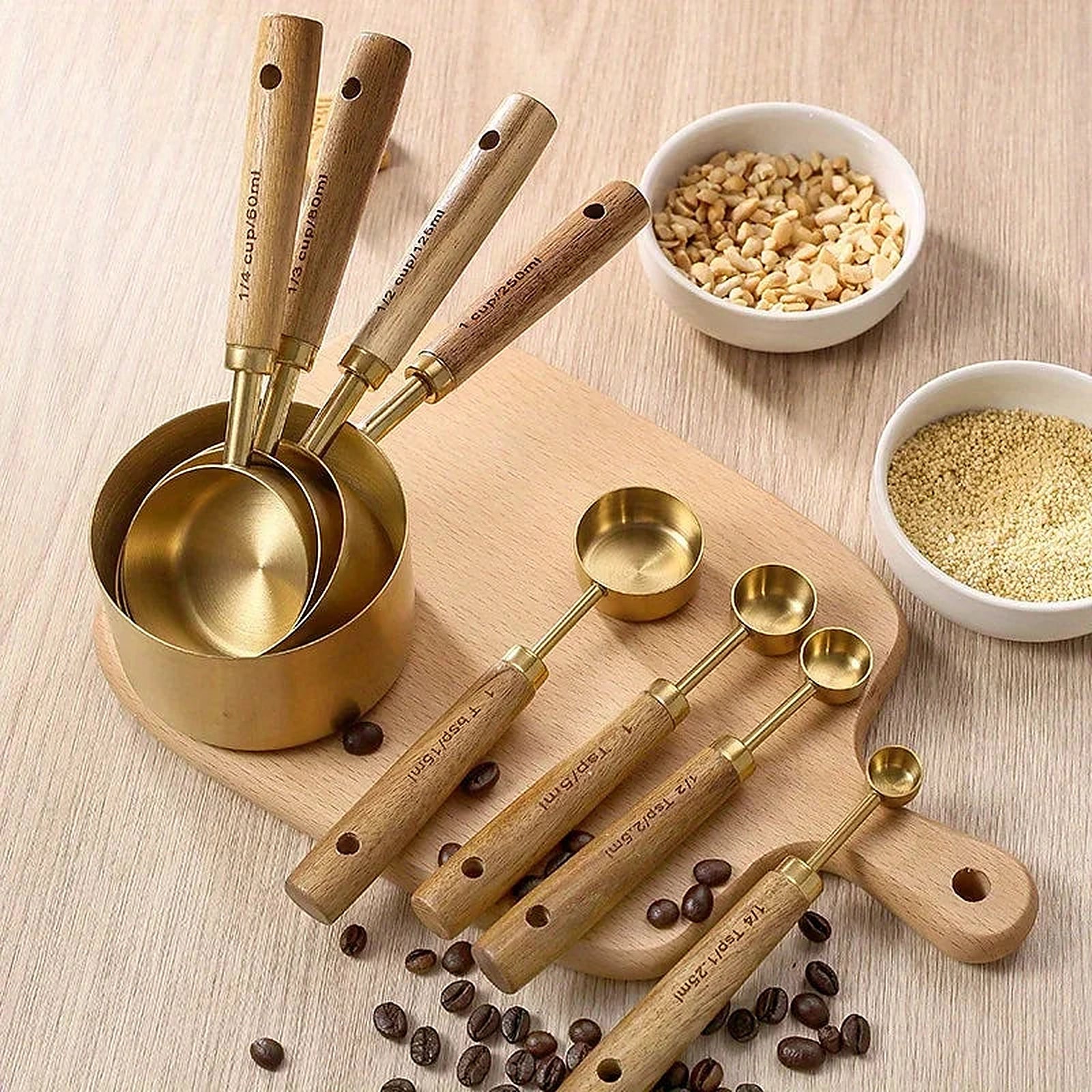 Tasses et cuillères doseuses dorées à manches en bois disposées sur une planche en bois avec des grains de café.