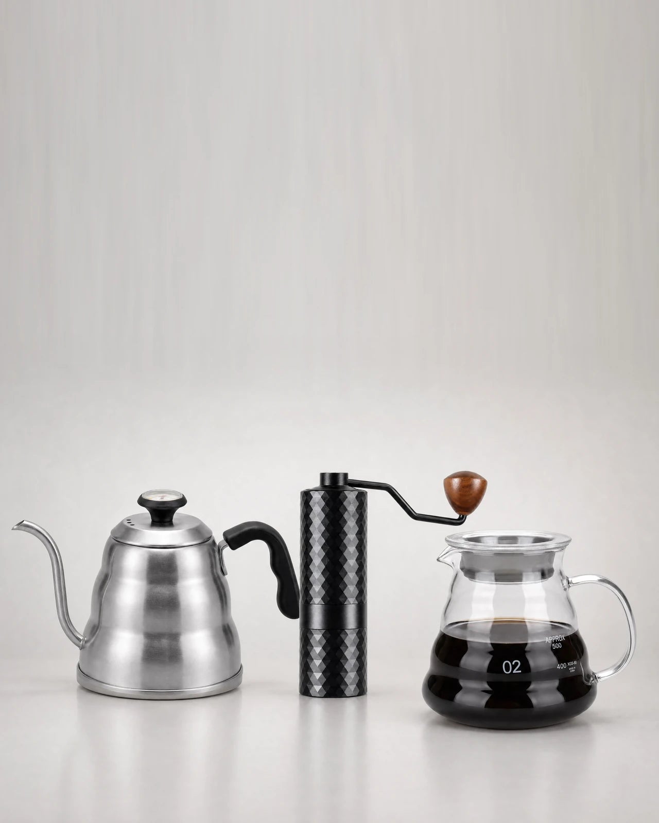 Cafetière moka inox, moulin manuel et bouilloire col de cygne sur plan de travail bois