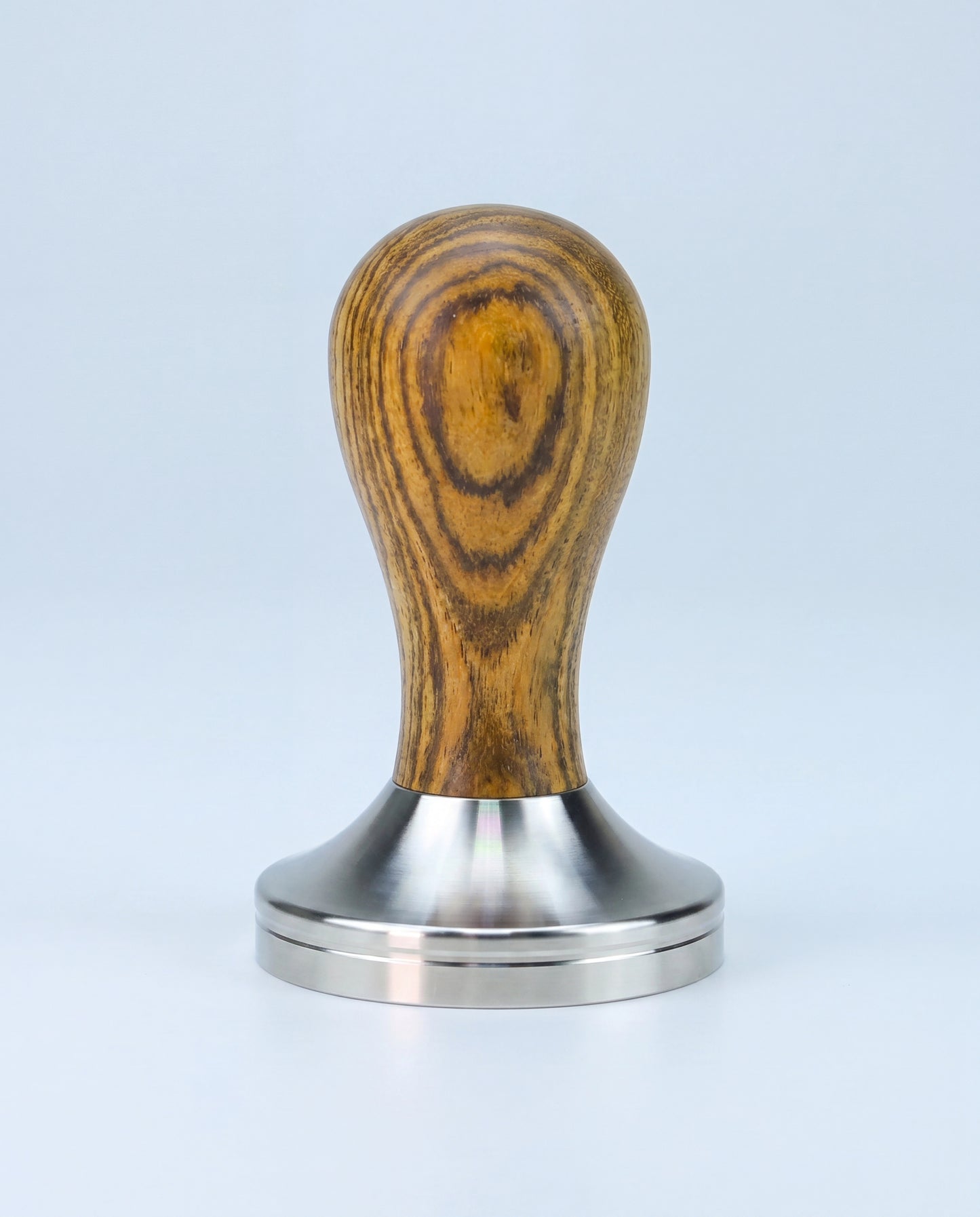 Tamper à espresso à manche galbé en bois et base en inox, vu de profil sur fond clair.
