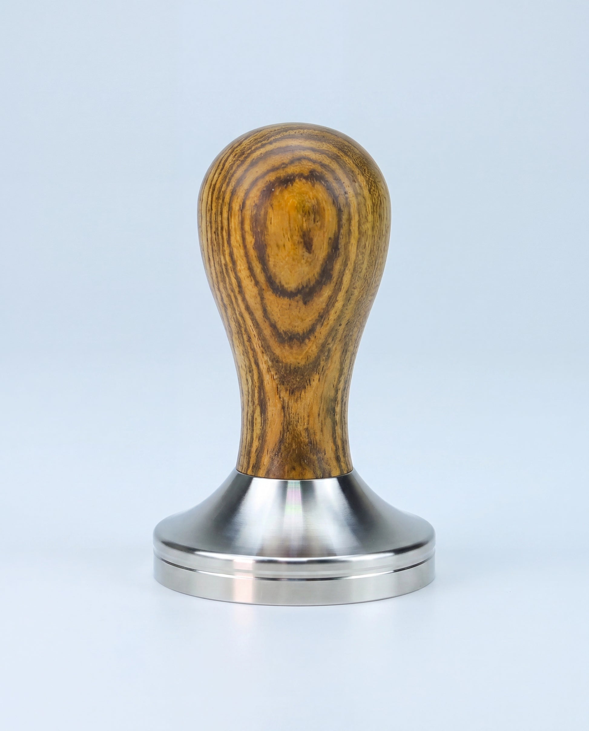 Tamper à espresso à manche galbé en bois et base en inox, vu de profil sur fond clair.