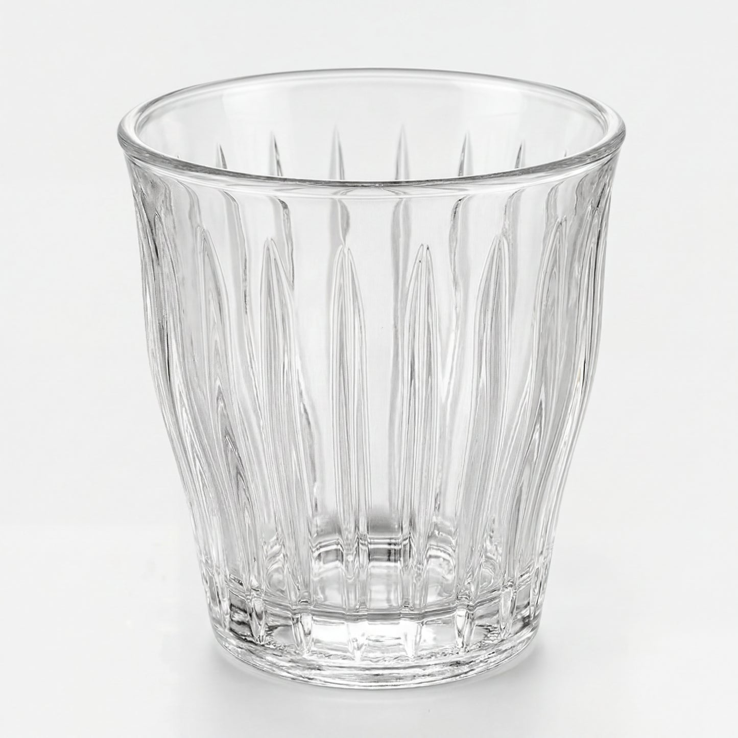 Verre à espresso transparent à facettes verticales, vue de trois-quarts sur fond blanc.